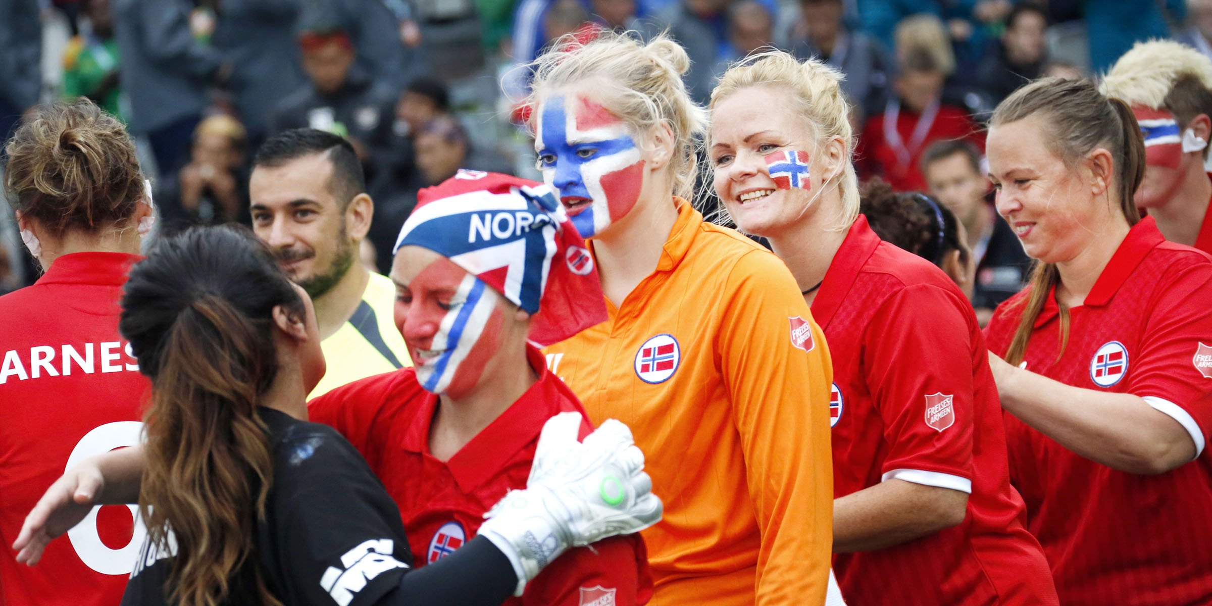 Kvinnelige fotballspillere med norsk flagg malt i ansiktet smiler.