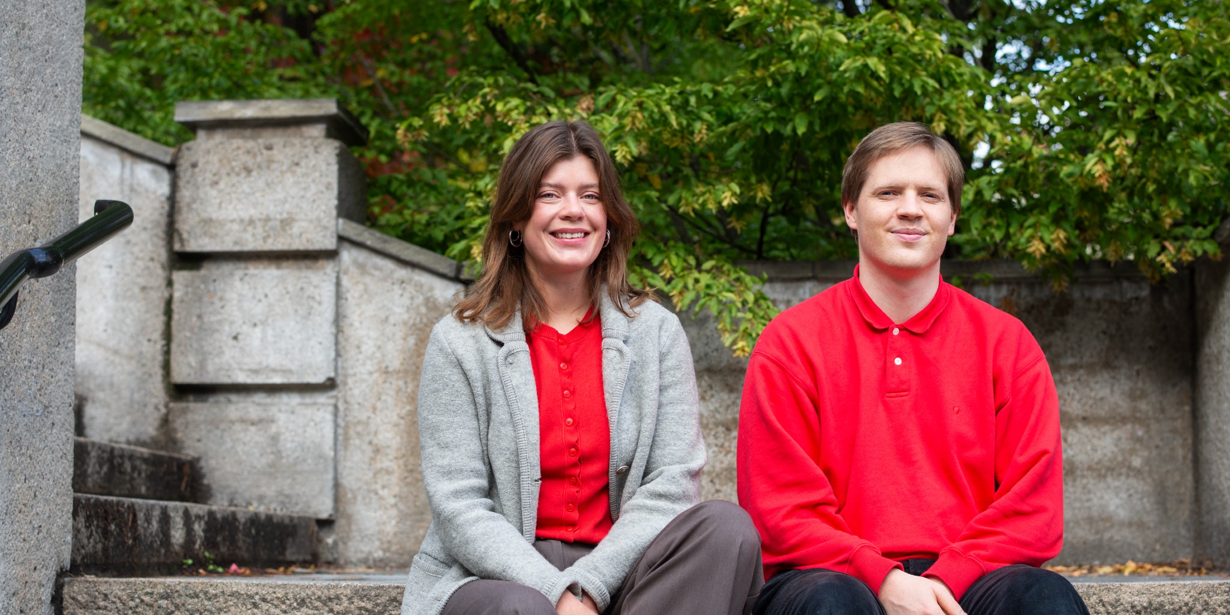 Portrait of the student ombuds Rebekka and Martin sitting outdoors on a stone staircase.