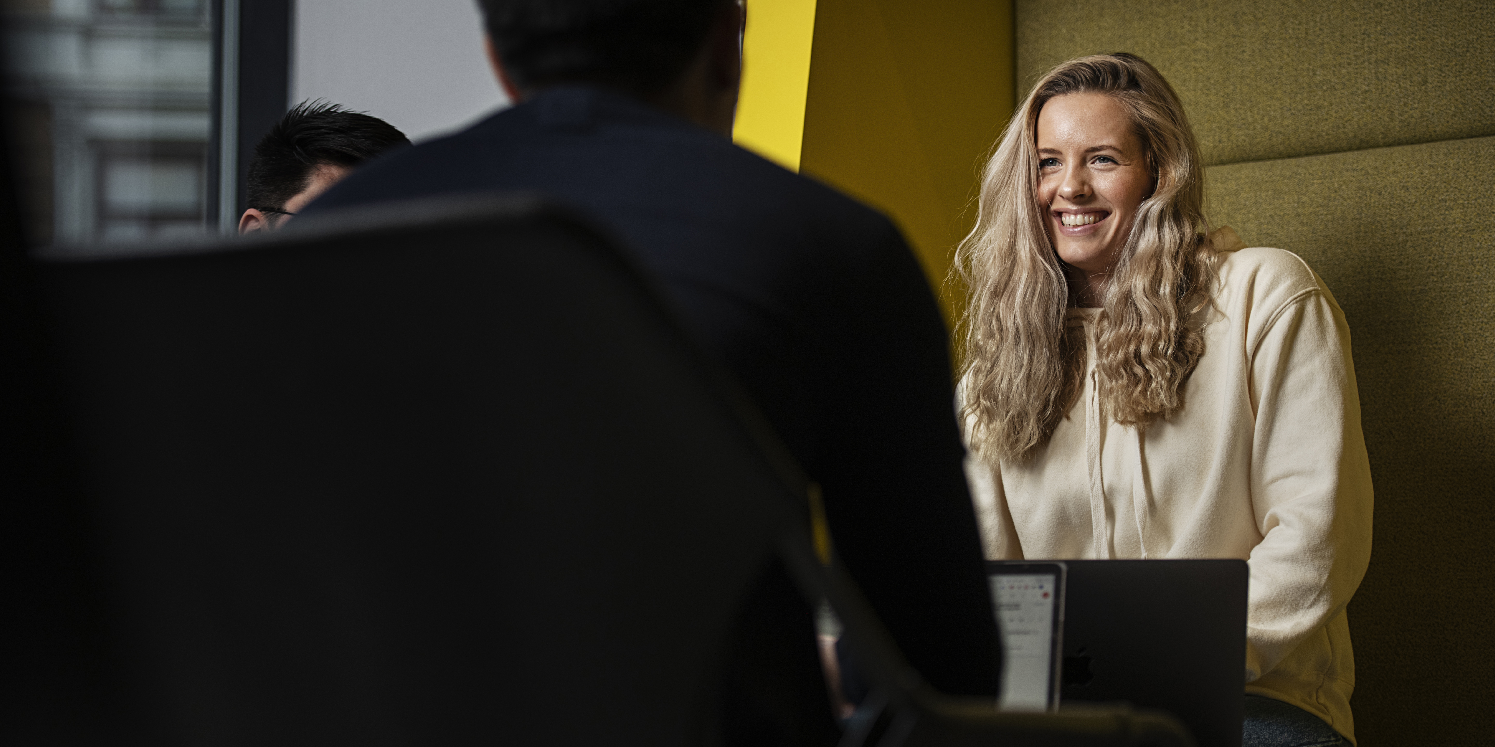 A smiling woman sitting near a window.