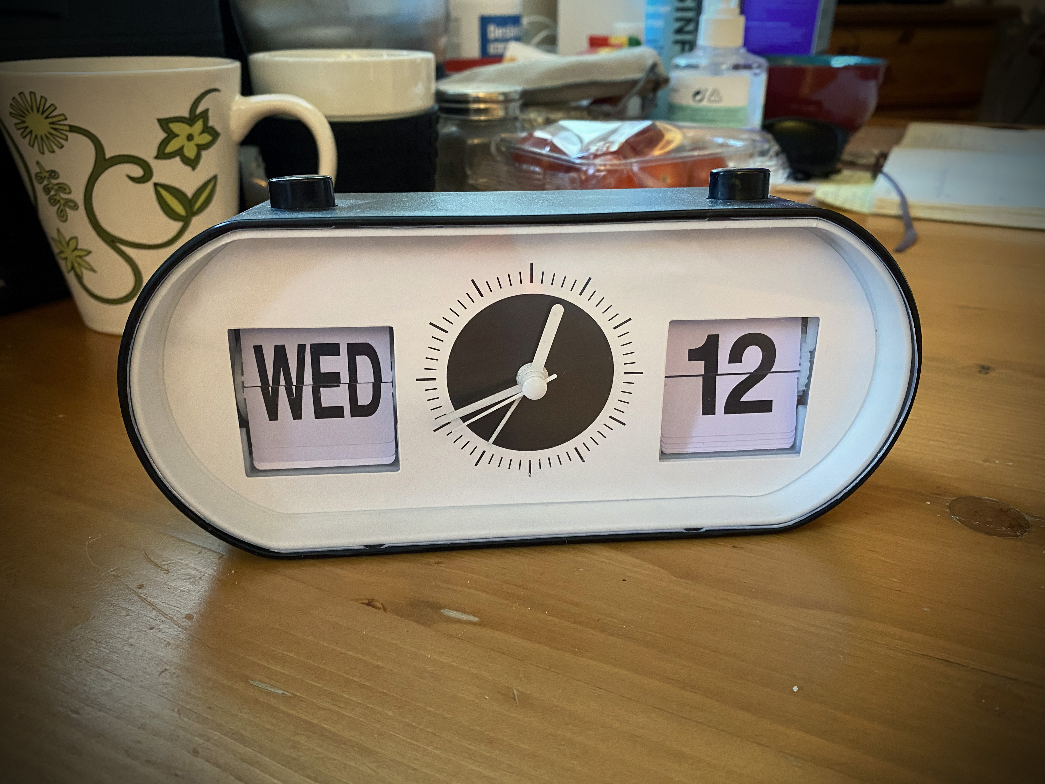 Klokke med kalender på bord med kopp og skrivesaker