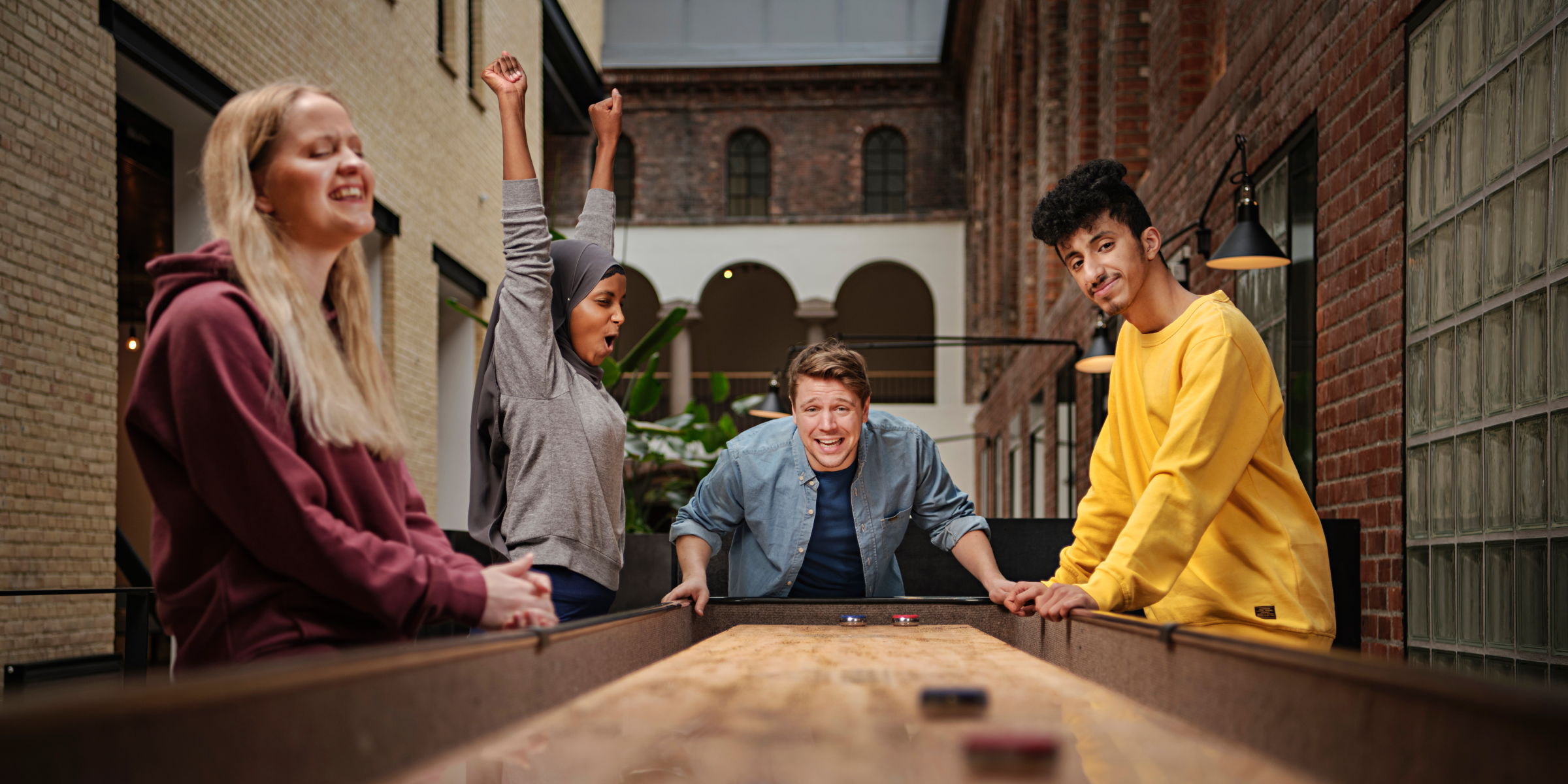 Four OsloMet students play shuffleboard in Pilestredet 52.