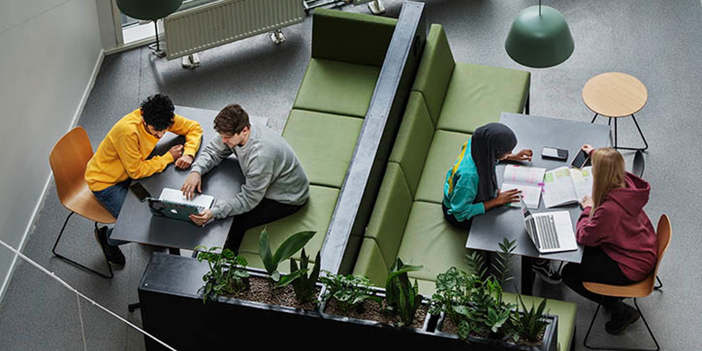 Fire studenter, sett ovenfra sitter i sofaer og ser sammen på PCer