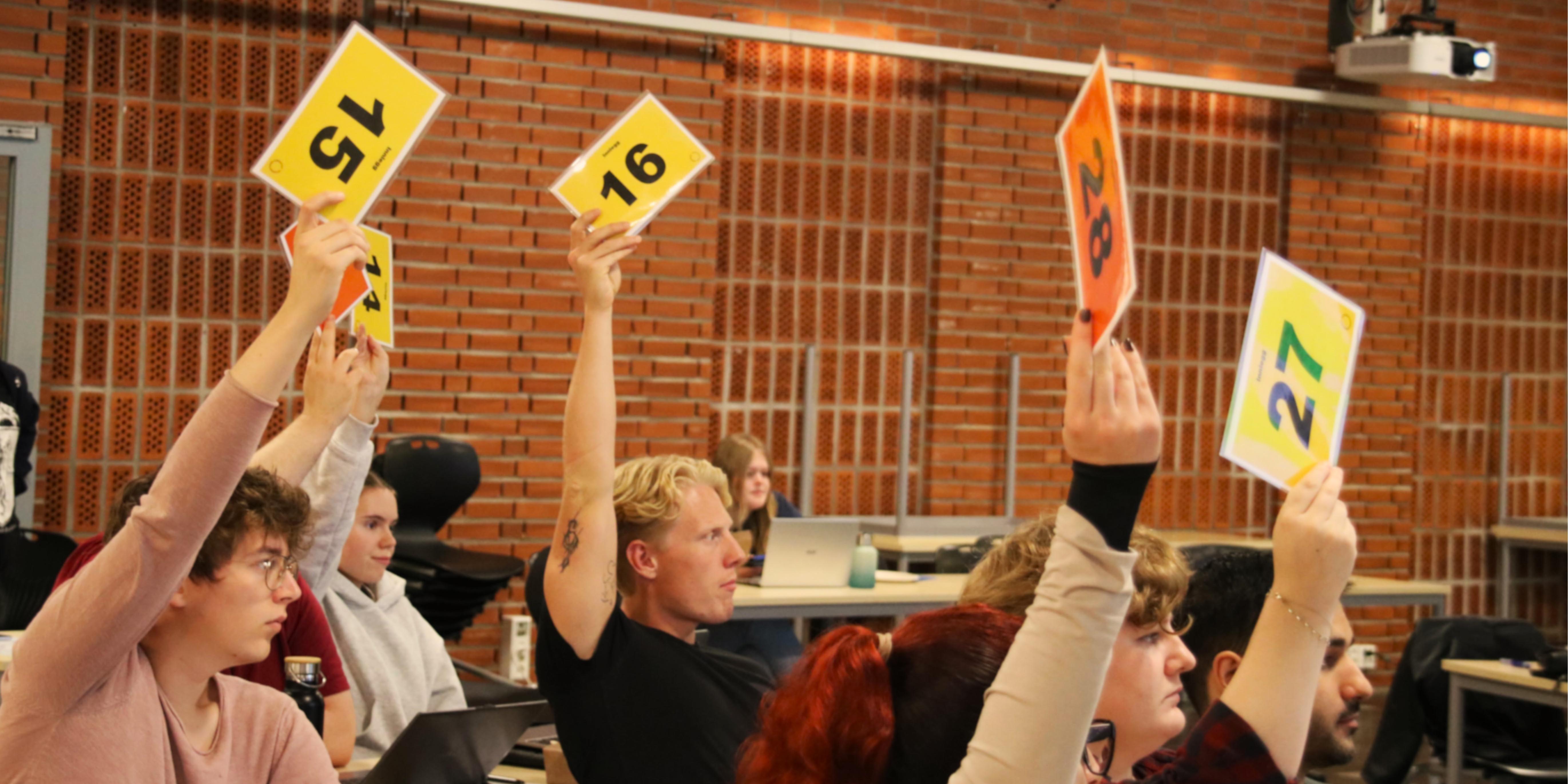 Students in the Studentparliament voting with their hands in the air.