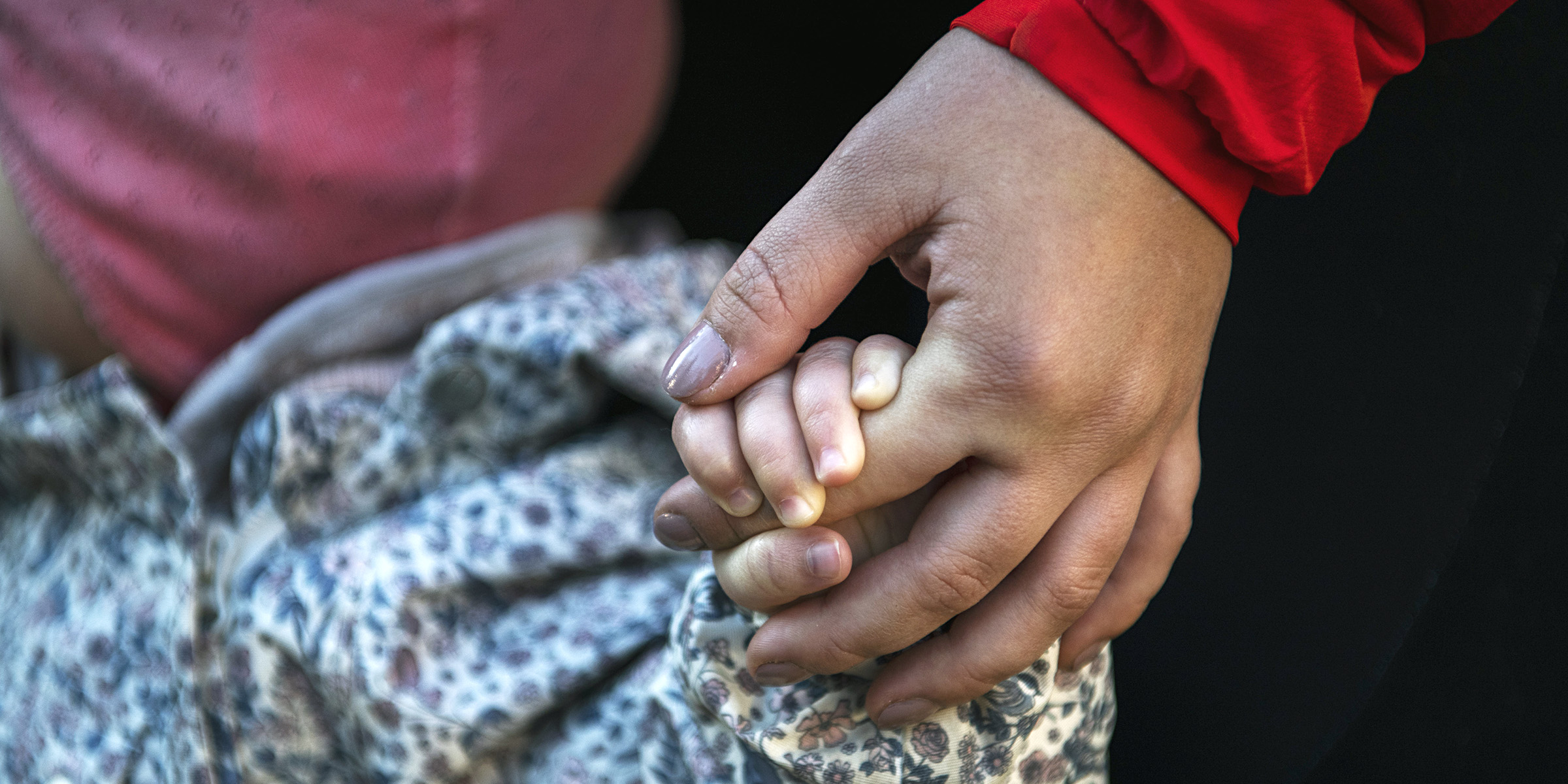 Close-up of an adult hand holding a child's hand.